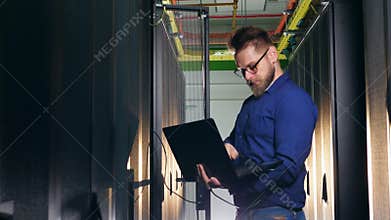 Computer engineer is connecting his laptop to the server