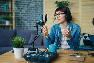 Attractive young lady speaking in microphone gesturing in studio