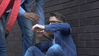 Cruel group of teenagers throwing books on nerd boy, aggression and rudeness