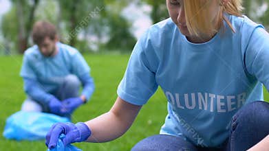Female eco-activist collecting rubbish in park, nature protection love to nature