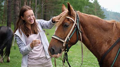 Pretty woman smiles stroking smooth the horse`s mane. slow motion