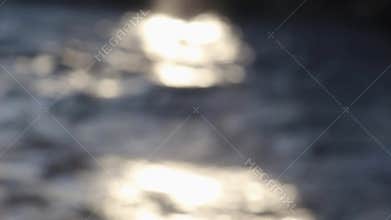 The defocused view of river stream water slowly flowing through natural rock beach in morning. Abstract nature background.