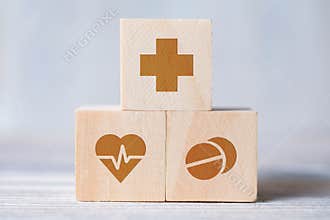 Cubes with medical icons of cross, heart with cardiogram, pills on wooden background