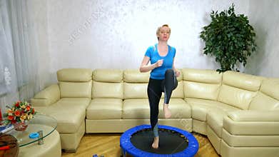 Woman goes in for sports on a trampoline at home. Cardio.