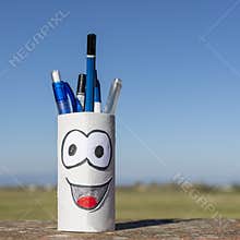 Creative reuse of a finished toilet roll turned into a pen holder against a beautiful blue sky