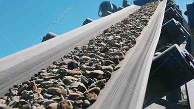 Stones moving on a belt line on a crushing machine.