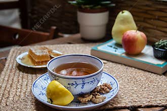 Morning setup on wooden table at balcony for morning relaxation with books, cup of tea, teapot, organic honey, green tea leaves
