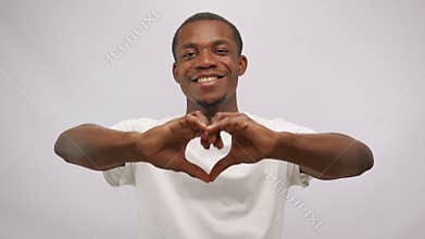 Happy african american man making heart shape sign with hands looking at camera.