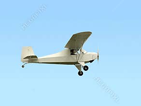 Single engine ultralight plane flying in the blue sky with white clouds