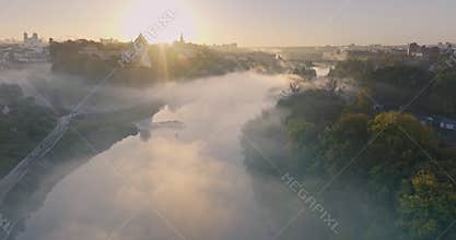 flight over morning river with mist and fog overlooking old medieval castle and city with historic buildings
