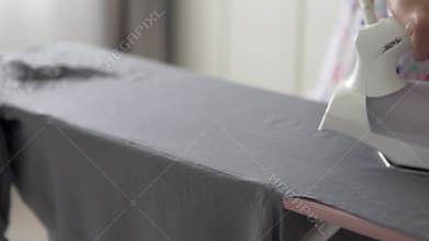 Close-up, a woman ironing clothes at home on an ironing board