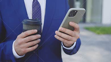 Close Up Of Man Hands Typing, Texting, Browsing Mobile Phone Holding Coffee. Manager Businessman Working With Smartphone