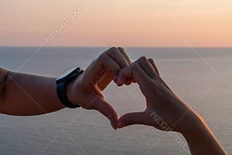 Hands heart sea sanset. Hands forming a heart shape made against the sun sky of a sunrise or sunset on a beach