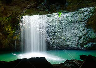A waterfall flowing through a Natural rock arch.