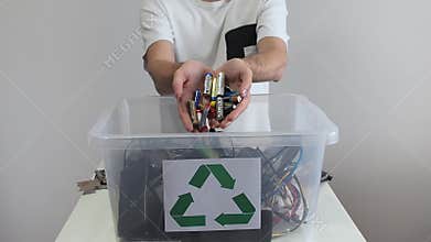 Minsk, Belarus - 29 May, 2022. Man hands putting many different old used batteries in container with recycling symbol