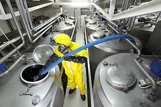 technician filling large silver tank in factory
