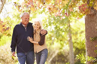 Senior Couple Walking Through Autumn Woodland
