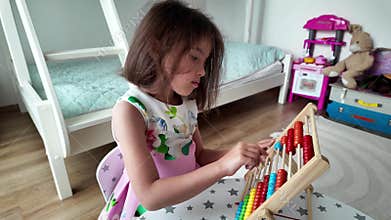 Focused Young Girl Learning with Wooden Abacus at Home.