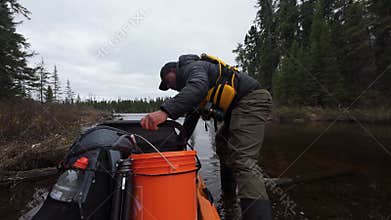 photographer portaging with camera equipment walks his kayak through shallow waters