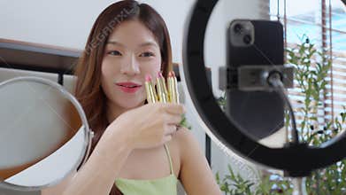 Young asian beauty influencer review multiple lipstick shades at home, cosmetic product of content creator on social media and