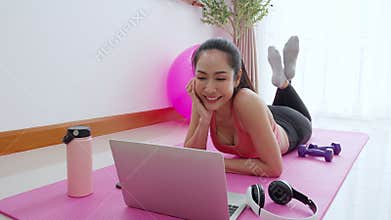 Young asian woman video call with friends after practice yoga and workout for relax in living room at home, woman using notebook