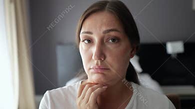 Woman examines neck sagging skin looking closely in mirror