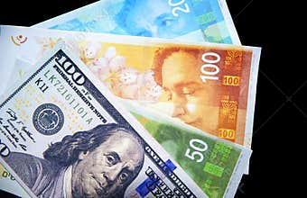 Israeli Currency Shekel with United States Dollar bill on the black backdrop. Business and trade concept between America and