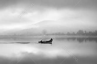 A fisherman on a boat, on a misty morning