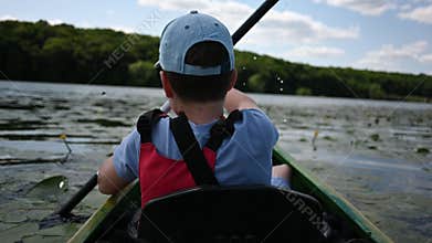 Young Boy Enjoys Paddling His Kayak on a Sunny Summer Lake Adventure