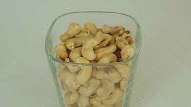 Glass cup full of raw cashew nuts on light background. Healthy vegan snack and natural source of protein and fats. Organic food