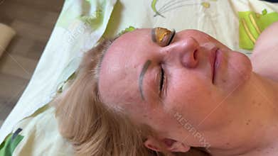 Correction of a shape of eyebrows with hot wax. Brow master applying wax on the eyebrow of female face of a brunette