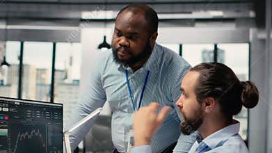 Coworkers collaborate on trading strategies in office, review stock market data