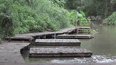 Wooden bridge and small wooden dock flanking river in forest.