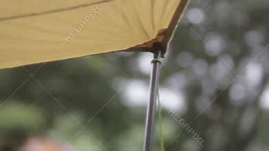 Raindrops falling from awning tarp tent at campsite.
