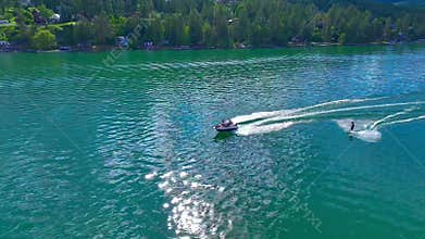 Aerial view of a person doing water skiing in a lake near the shore, under cloudy sky at the daytime