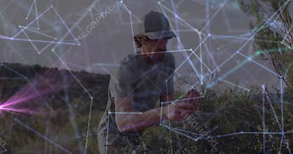 Man crouching in arid scrubland, inspecting plant samples, showing technology network overlay