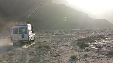 Off-road safari vehicle driving through egyptian desert at sunset