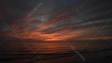 Dramatic red sunset with waves coming to the shore