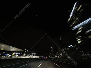 Nighttime urban highway with motion blur, empty lanes, glowing city towers