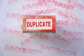 Red duplicate rubber stamp on white paper surrounded by multiple faded red stamp marks
