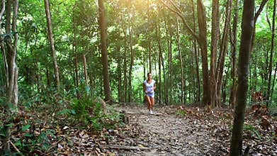 Young fitness woman running in jungle forest on