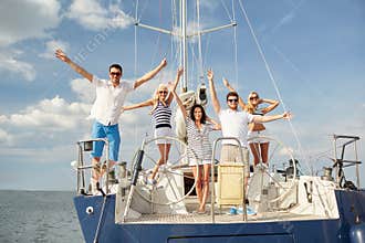Smiling friends sitting on yacht deck and greeting