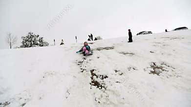 Girl sledding down snow hill