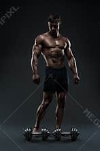 Stunning muscular bodybuilder posing over black background