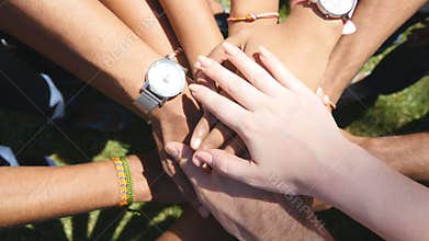 Arm of all races and colors stacked together one by one in unity and teamwork and then raised. Many multiracial hands