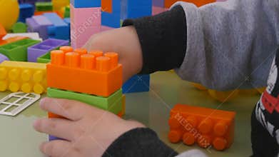 Children play in color cubes. Close-up construction of children`s designer