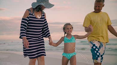 Happy family walking on ocean coast. Silhouettes sunset.