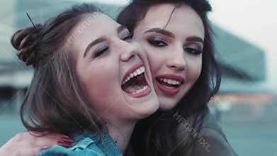 Close up view of two young girls with beautiful makeup going crazy, laughing, hugging. Natural beauty, jeans wear