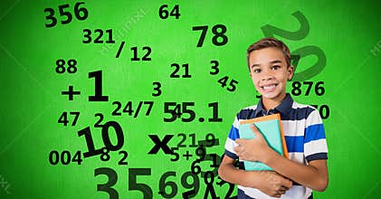 Digitally generated image of boy holding books with numbers flying against green background
