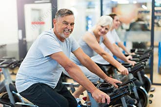 Seniors on exercise bikes in spinning class at gym